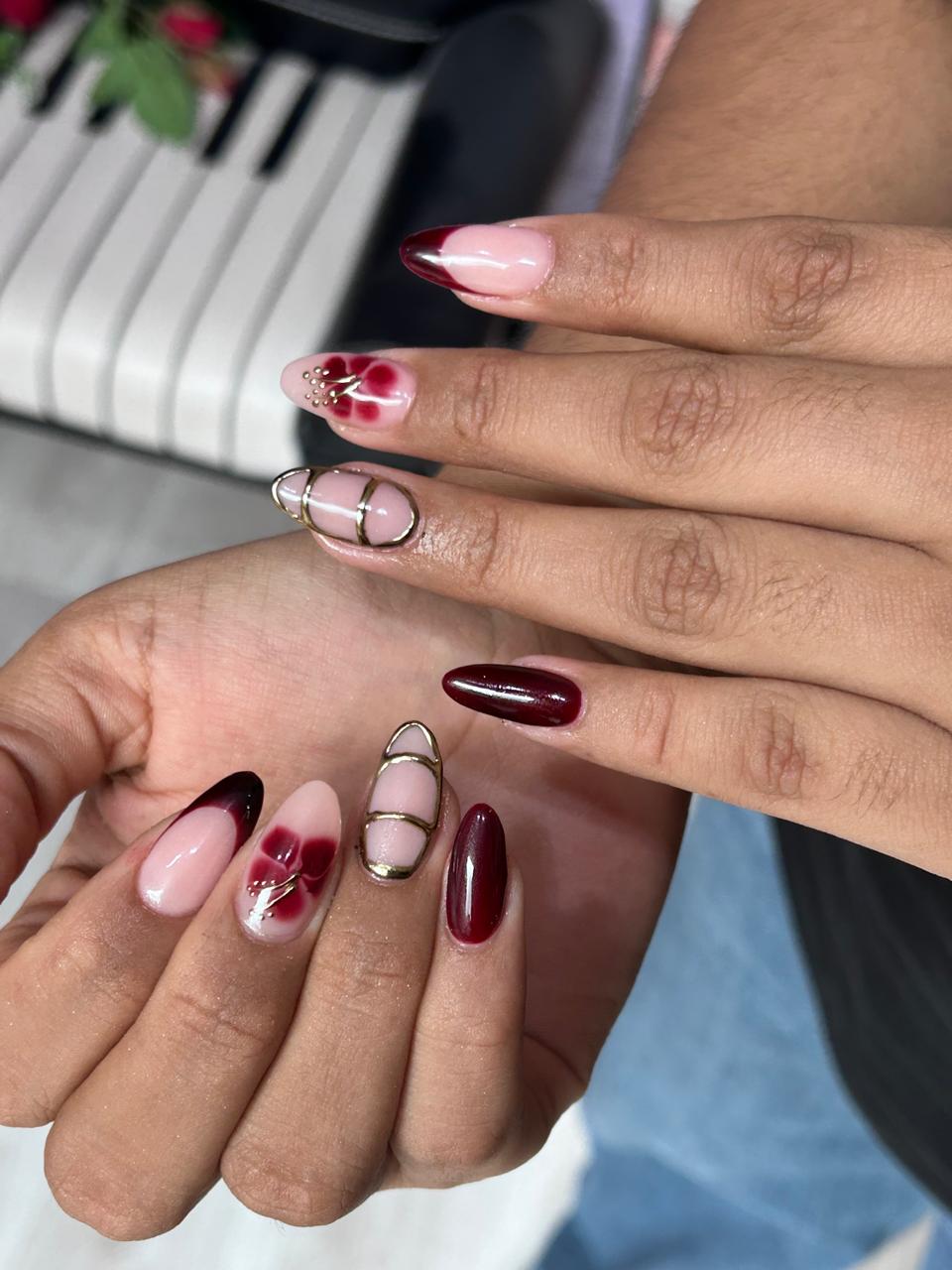 Manicura LUZLU amb tons bordeus, flors i detalls daurats